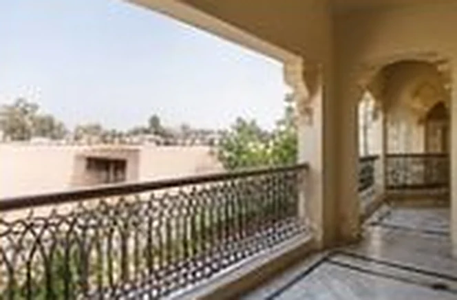 Arched veranda with a wrought-iron railing overlooking trees