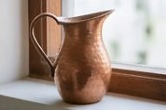 Hammered copper jug on a sunlit window sill