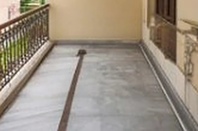 Long balcony corridor with a stone floor and iron railing