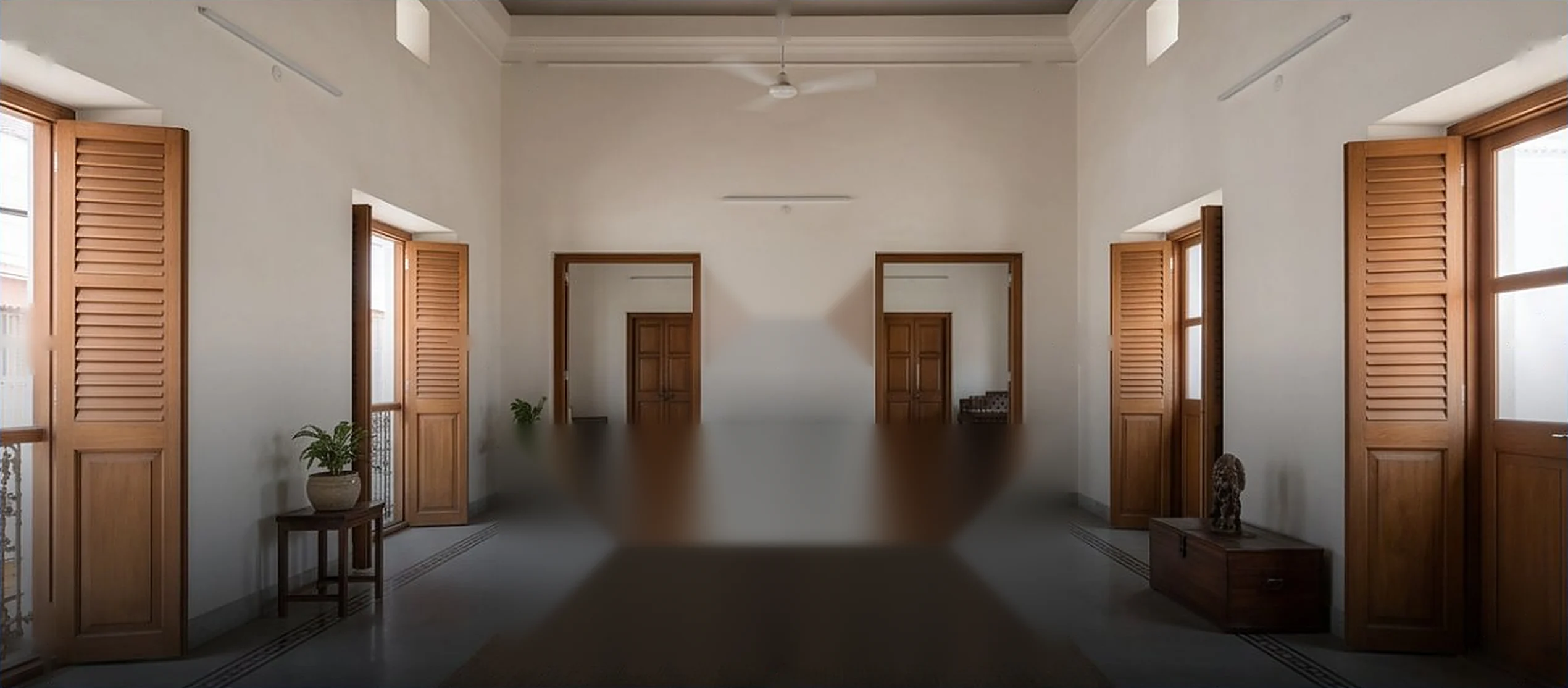 High-ceilinged Indian apartment hall with pale walls and open wooden shutters